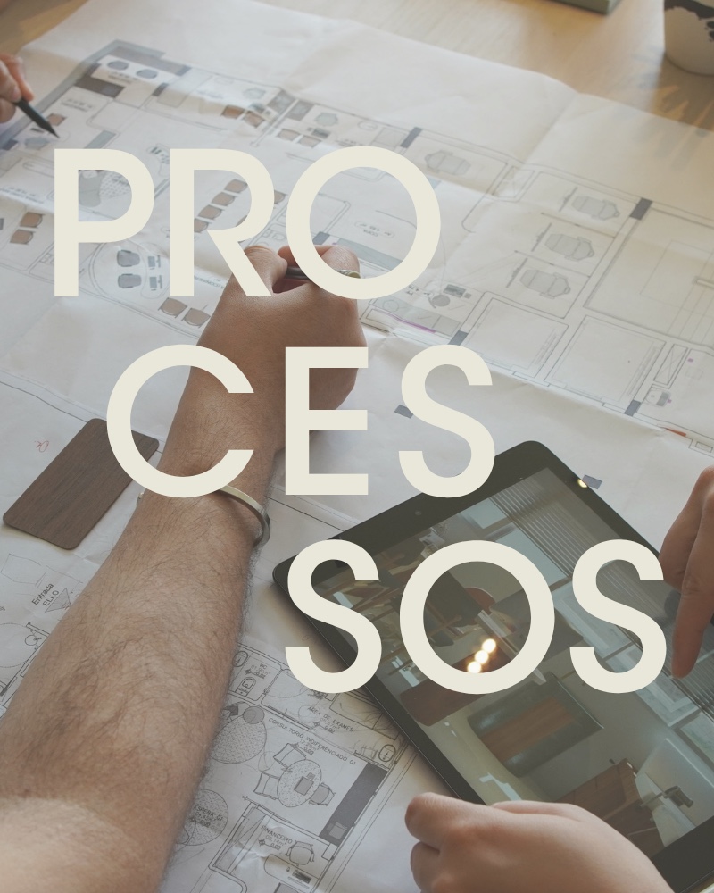 Processos — mãos sobre plantas baixas, tablet e amostra de madeira na mesa do estúdio
